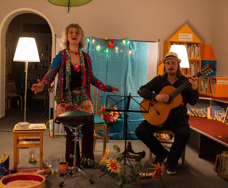Sängerin und Gitarrist in buntem Raum