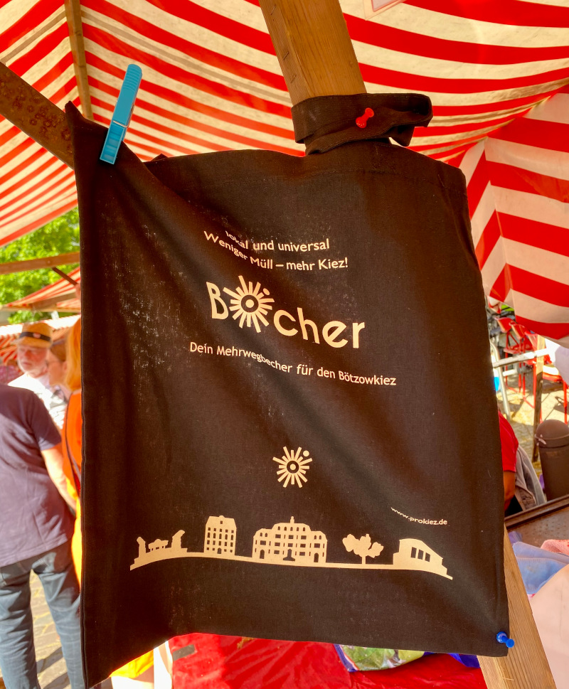 Beutel mit Aufschrift BÖcher und Kiezsilhouette vor rot-weißer Markise