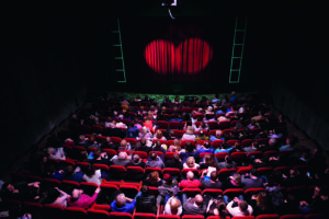 Voller Theatersaal mit geschlossenem Vorhang